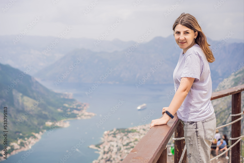 Woman tourist enjoys the view of Kotor. Montenegro. Bay of Kotor, Gulf of Kotor, Boka Kotorska and walled old city. Travel to Montenegro concept. Fortifications of Kotor is on UNESCO World Heritage Woman tourist enjoys the view of Kotor. Montenegro. Bay of Kotor, Gulf of Kotor, Boka Kotorska and walled old city. Travel to Montenegro concept. Fortifications of Kotor is on UNESCO World Heritage