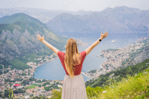 Woman tourist enjoys the view of Kotor. Montenegro. Bay of Kotor, Gulf of Kotor, Boka Kotorska and walled old city. Travel to Montenegro concept. Fortifications of Kotor is on UNESCO World Heritage