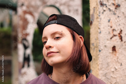 Portrait of punk teenage girl with pierced eyebrow in cap backwards