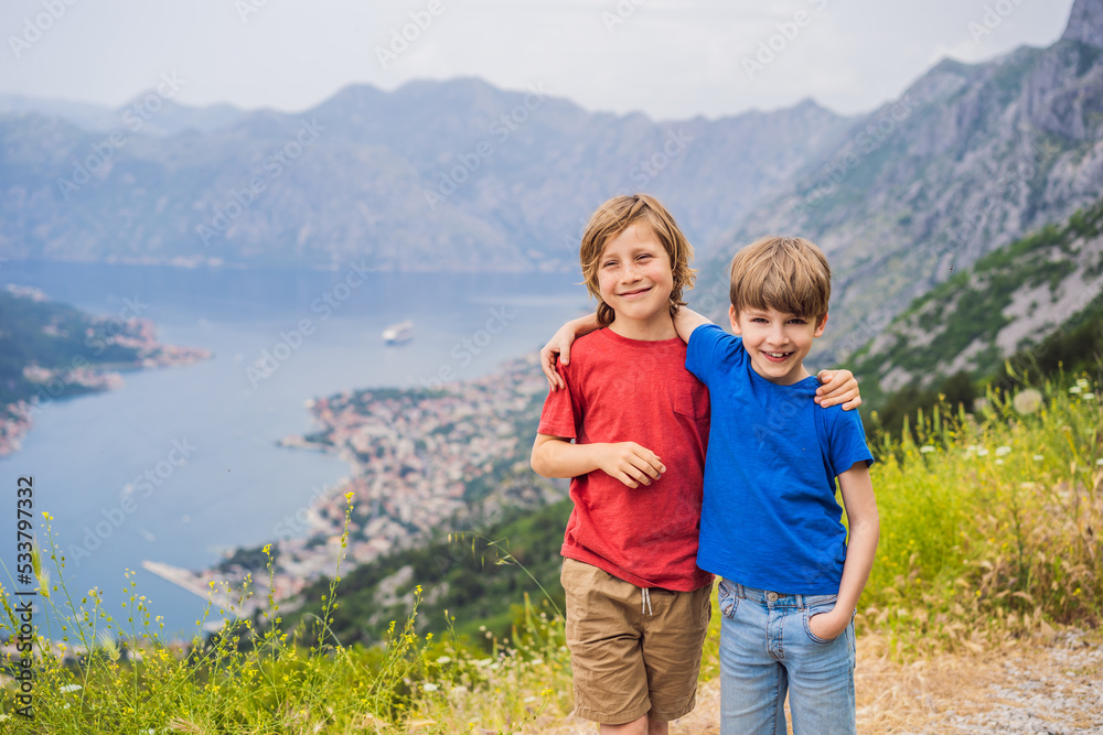 Two boys friend enjoys the view of Kotor. Montenegro. Bay of Kotor, Gulf of Kotor, Boka Kotorska and walled old city. Travel to Montenegro concept. Fortifications of Kotor is on UNESCO World Heritage Two boys friend enjoys the view of Kotor. Montenegro. Bay of Kotor, Gulf of Kotor, Boka Kotorska and walled old city. Travel to Montenegro concept. Fortifications of Kotor is on UNESCO World Heritage