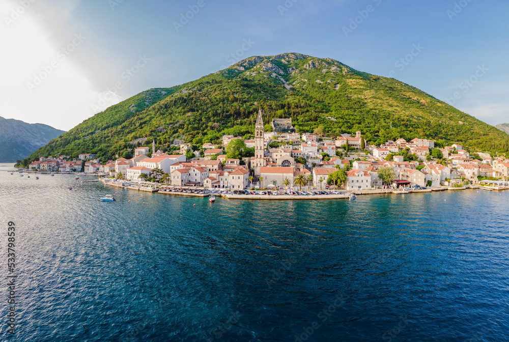 Scenic panorama view of the historic town of Perast at famous Bay of Kotor with blooming flowers on a beautiful sunny day with blue sky and clouds in summer, Montenegro, southern Europe Portrait of a