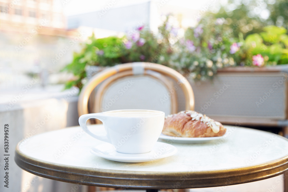 Cup of coffee and croissant on a patio table.
Close up, blurred background. Cup of coffee and croissant on a patio table.
Close up, blurred background.