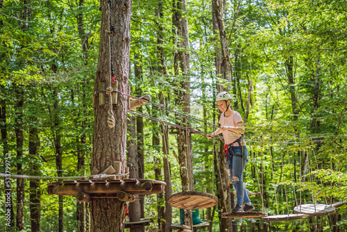 Happy women girl female gliding climbing in extreme road trolley zipline in forest on carabiner safety link on tree to tree top rope adventure park. Family weekend children kids activities concept