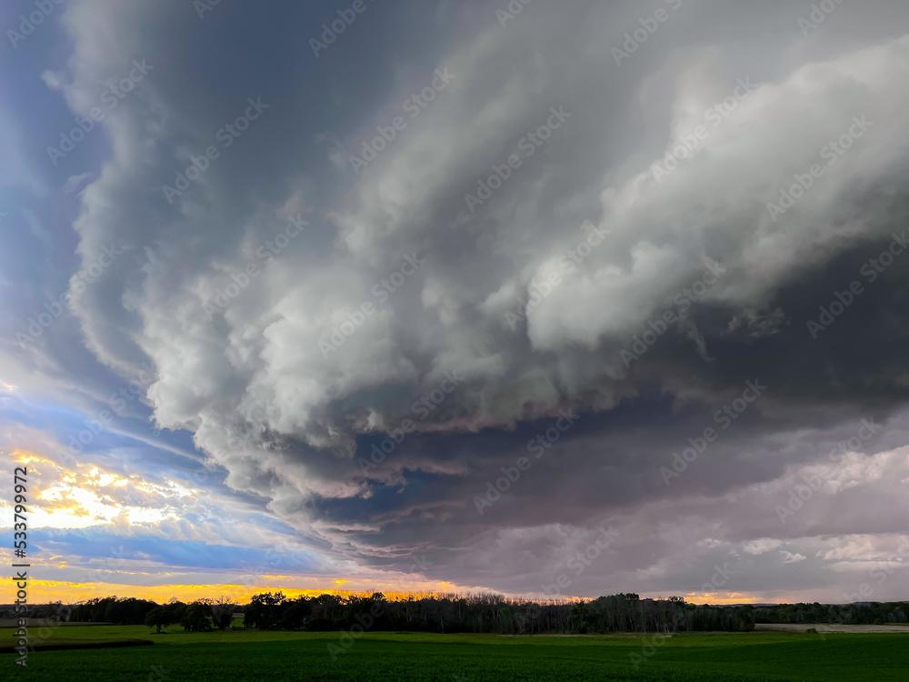 A shelf cloud before a thunderstorm in farm country at sunset. A shelf cloud before a thunderstorm in farm country at sunset.