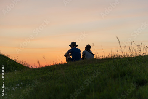 Moody photo of couple who sitting under the sunset sky © Jinchoiphotography