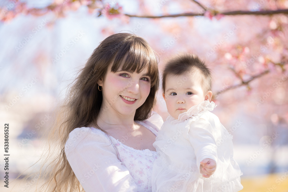 Obraz premium 赤ちゃんとお母さん、桜の木の下で