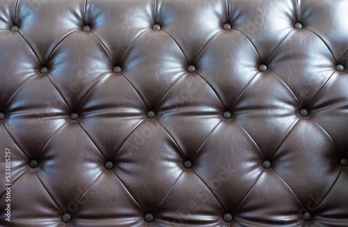 Closeup of Natural brown leather texture with in the shadow. Brown leather texture background. Background of a leather armchair.