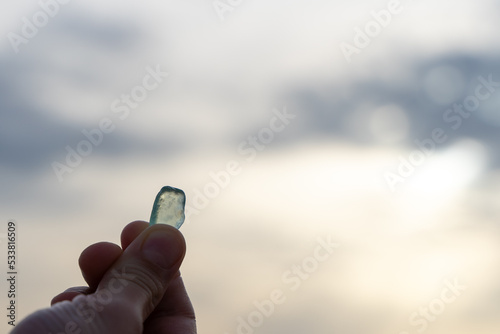 Blue smooth glass from the sea in the hand of a man against the sky