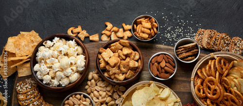 Assortment of salty snacks on dark background.