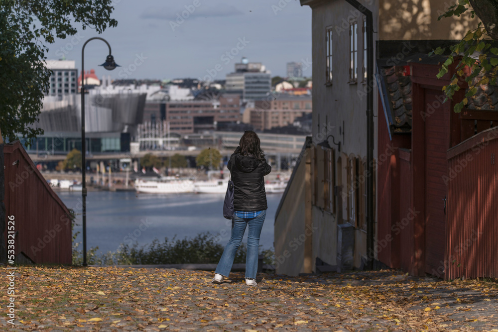 Tourist taking picture over the bay Riddarholmsfjärden from a vista point in the district Södermalm an autumn day in Stockholm