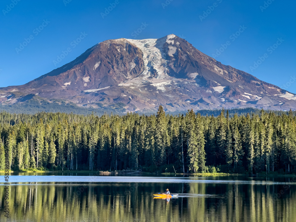 A kayaker paddles across a lake overlooking a Cascades volcano