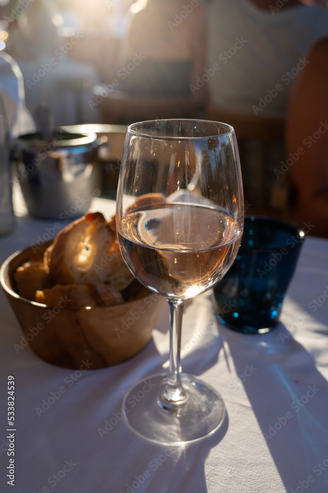 Dinner at sunset in French restaurant with cold dry rose wine in Port Grimaud, summer vacation on French Riviera, France Dinner at sunset in French restaurant with cold dry rose wine in Port Grimaud, summer vacation on French Riviera, France