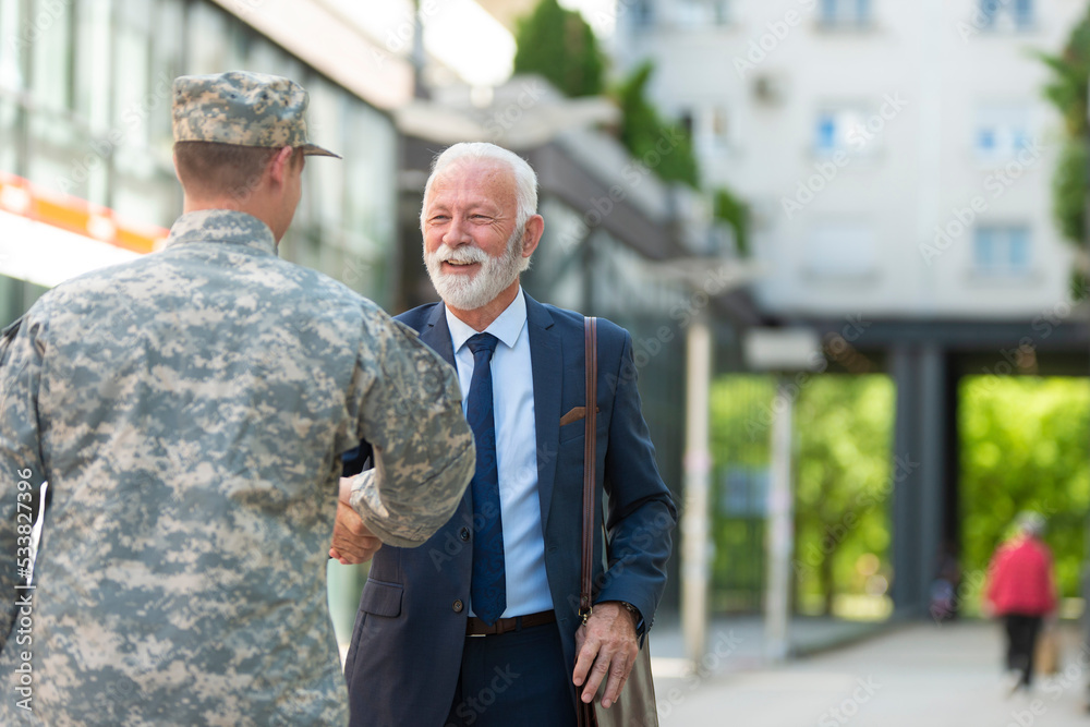 Senior businessman shaking hands with soilder outdoor Senior businessman shaking hands with soilder outdoor