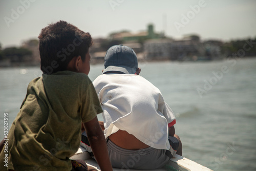 Foto two poor children riding the front of a fishing boat third world country poverty