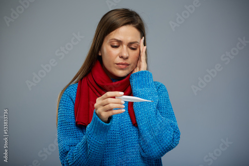 Sick woman with cold flu touching her head and looking on thermometer. Isolated portrait.