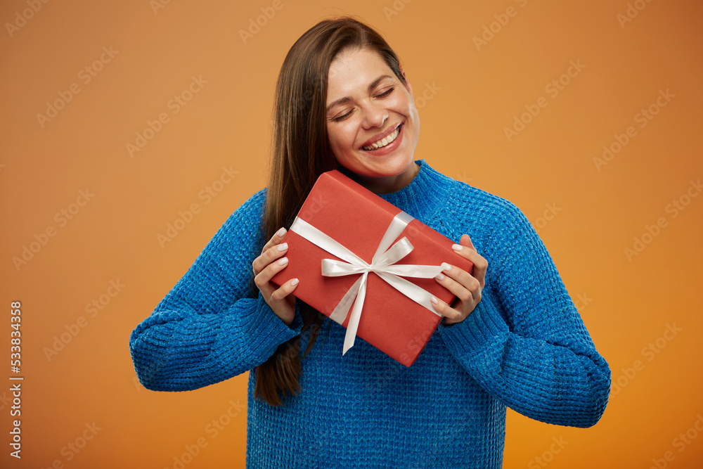 Happy hollyday with smiling woman in blue sweater holding present. Isolated portrait on orange background. Happy hollyday with smiling woman in blue sweater holding present. Isolated portrait on orange background.