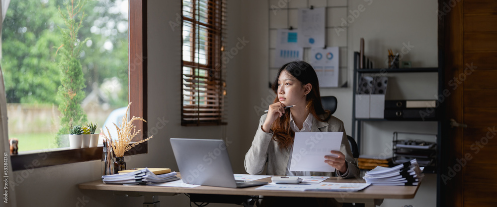 Thoughtful woman checking financial documents, holding paperwork, calculating domestic bills or taxes, using laptop, unhappy pensive young female touching chin, unexpected debt or bankruptcy concept Thoughtful woman checking financial documents, holding paperwork, calculating domestic bills or taxes, using laptop, unhappy pensive young female touching chin, unexpected debt or bankruptcy concept