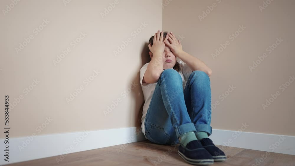 sad girl sitting in the corner crying a covered her indoor face with her hands. family violence abuse child concept. parents punished the child put in a corner. child in depression crying lifestyle