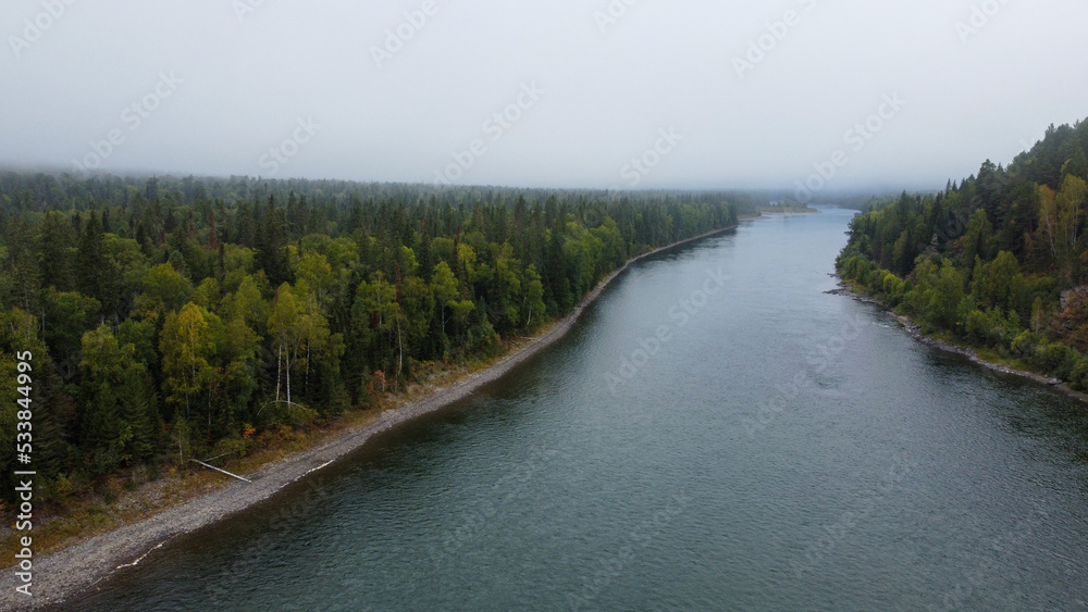 Wild nature landscape drone view with river and forest. Fog above water. Mountain Siberian river flow, water on stones, forest trees. aero view. Wild nature landscape drone view with river and forest. Fog above water. Mountain Siberian river flow, water on stones, forest trees. aero view.
