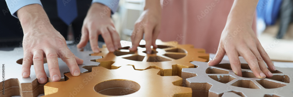 Businesspeople put wooden gears on workplace together, work in team Businesspeople put wooden gears on workplace together, work in team