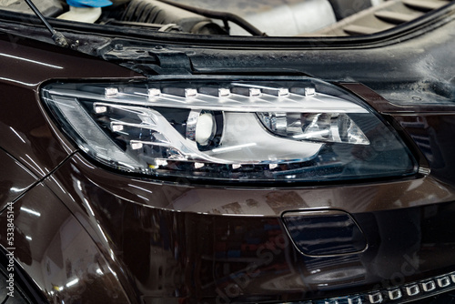 Car headlights and open hood in auto service garage © fotofabrika