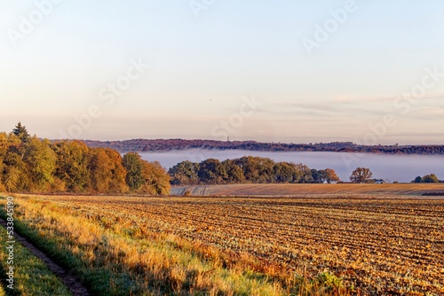 Across the fields at sunrise with mist in the distant valley