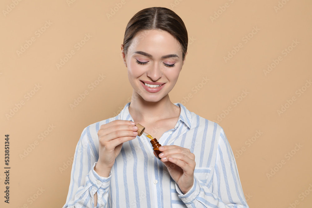 Young woman with bottle of essential oil on beige background Young woman with bottle of essential oil on beige background