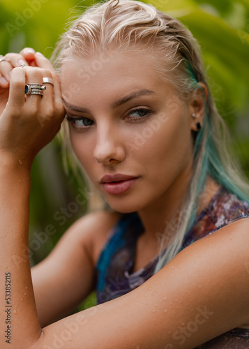 Gorgeous blond woman in sensual swimwear posing near pool on luxury tropical villa.