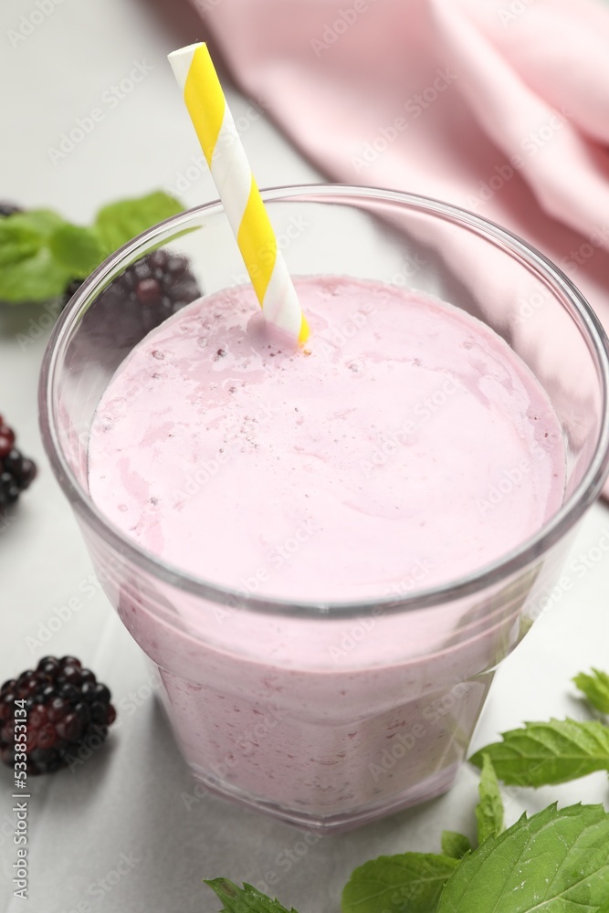 Delicious blackberry smoothie in glass with straw on white table, closeup Delicious blackberry smoothie in glass with straw on white table, closeup