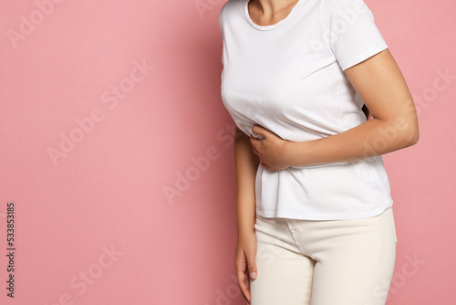 Young woman suffering from menstrual pain on pink background, closeup. Space for text