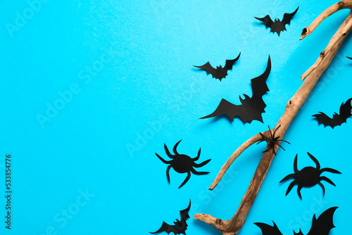 Flat lay composition with paper bats, spiders and wooden branch on light blue background, space for text. Halloween decor © New Africa