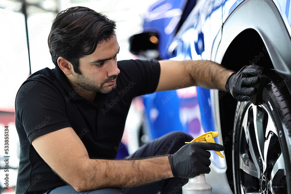 Car service worker polishing car wheels with microfiber cloth and waxing tire of car. Car service worker polishing car wheels with microfiber cloth and waxing tire of car.