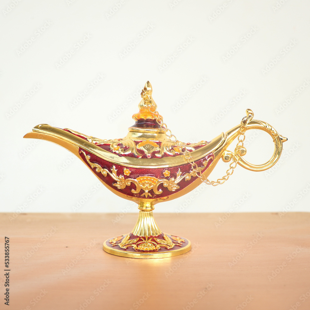 a gold magic lamp said to be holding a genie inside in fantasies isolated in a table in a white background a gold magic lamp said to be holding a genie inside in fantasies isolated in a table in a white background