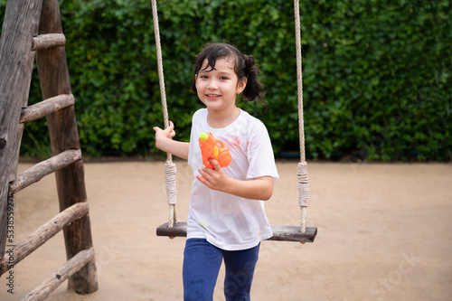 Foto Funny kid girl play squirt gun at play ground in the park