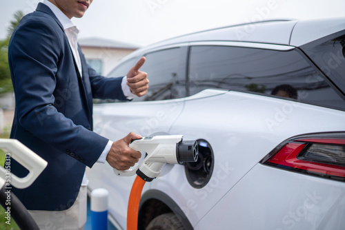 Young businessman holding an electric vehicle charger