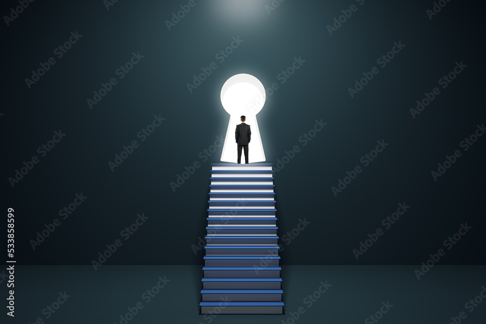 Φωτογραφία Back view of thoughtful young business man standing on stacked books ladder in concrete interior and looking out of keyhole window