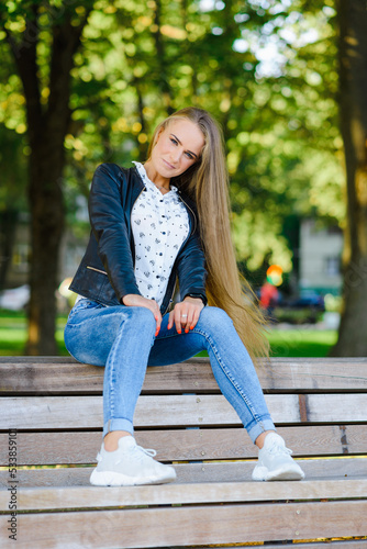 A beautiful fashion young city woman sitting on a bench.Summer,autumn day.Klaipeda,Lithuania.09-02-2022.