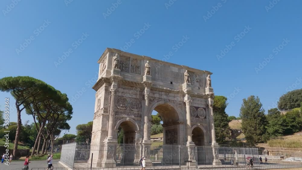 Arch of Constantine With Tourists Walking By On Sunny Clear Day With Blue Skies. Pan Down Arch of Constantine With Tourists Walking By On Sunny Clear Day With Blue Skies. Pan Down