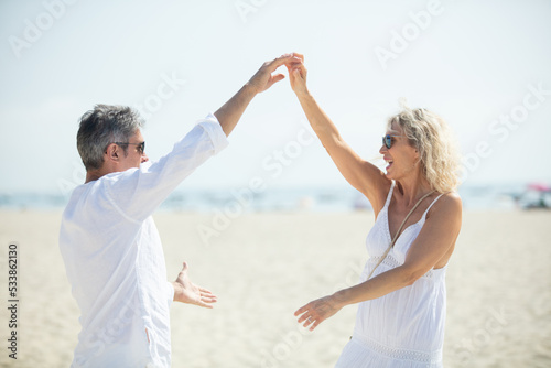 senior couple dancing at beach on sunny day