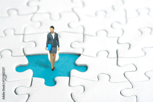 Miniature people toy figure photography. A businesswoman standing above missing piece of puzzle jigsaw