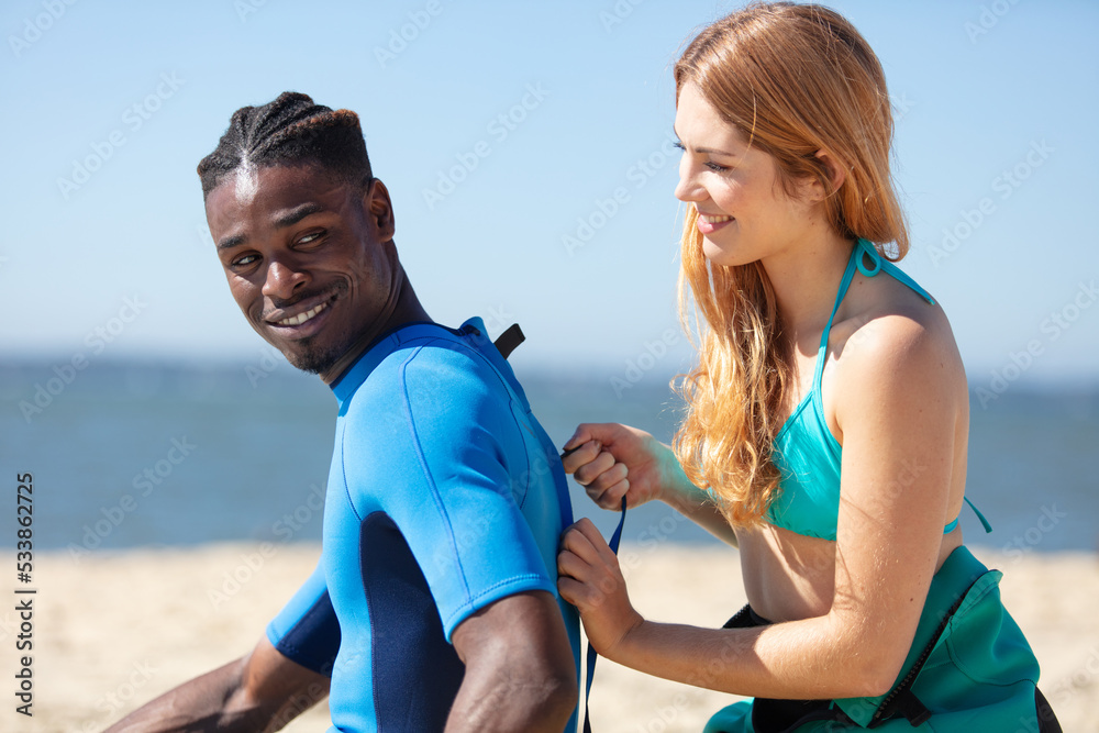 woman surfer zipping up her boyfriend surf wear woman surfer zipping up her boyfriend surf wear