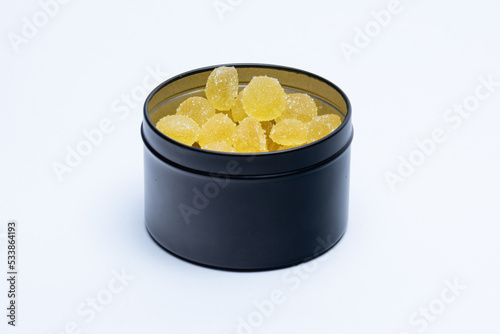 Yellow sugary gummies inside a black can.