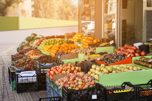 Many fruits and berries in crates selling near store on city street photo