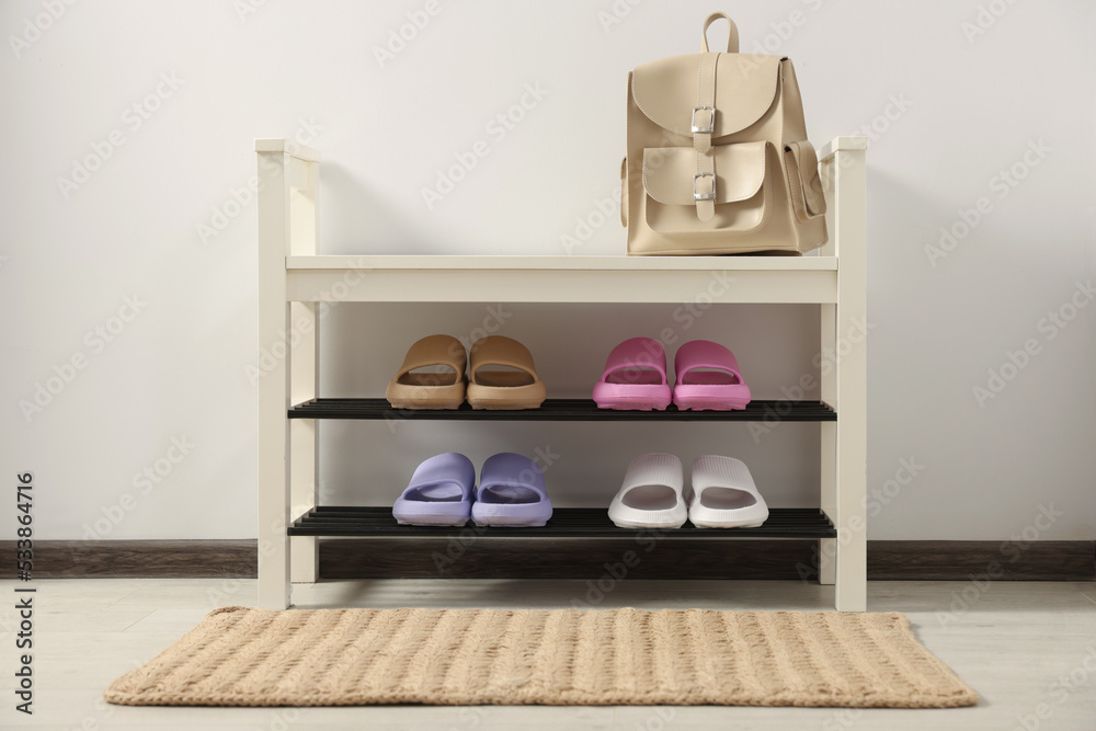 Fototapeta premium Storage bench with pairs of rubber slippers in room
