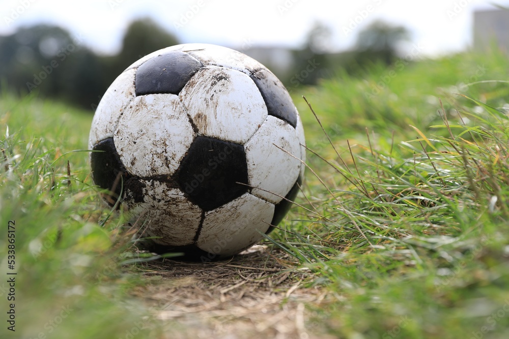 Fototapeta premium Dirty soccer ball on green grass outdoors, space for text