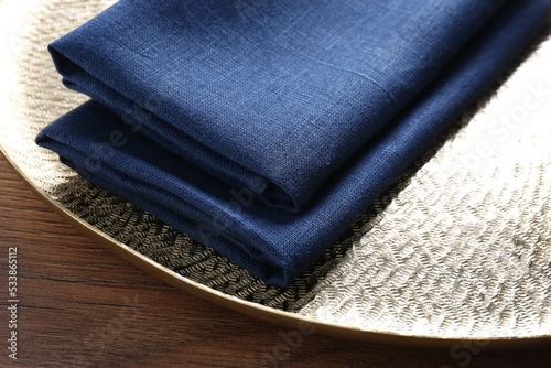 Tray with blue kitchen napkins on wooden table, closeup