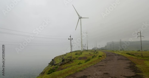 Road Between The Wind Turbines And Electricity Poles On A Foggy Morning. - wide photo