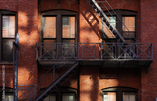 Dark metal stairs outside a brick landmark construction in Manhattan, New York, next to Brooklyn Bridge. Vintage architecture details in America.