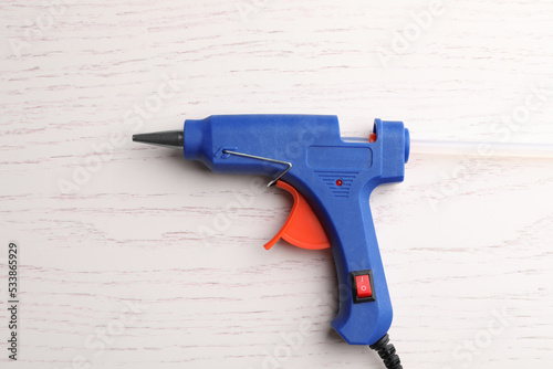 Dark blue glue gun on white wooden table, top view