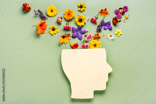 Mental health concept. Paper cut human head symbol and flowers on a green background